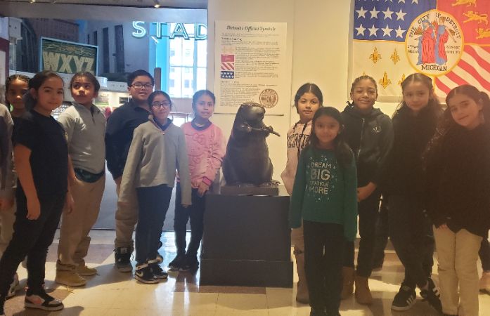 Students standing with a statue of a beaver at the Detroit Historical Museum